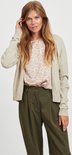 Model draagt een beige gebreid vest met een bloemenprint top en olijfgroene broek.