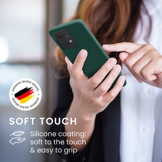 Vrouw houdt een telefoonhoesje in dennengroen vast, met een Duitse vlag-badge en tekst over zachte siliconen coating.