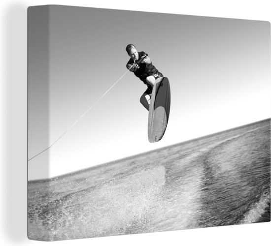 Canvas Schilderij Een man met een wetsuit is aan het wakeboarden op zee - zwart wit - Wanddecoratie