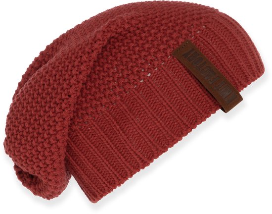 Rode gebreide muts met een label van Knit Factory.