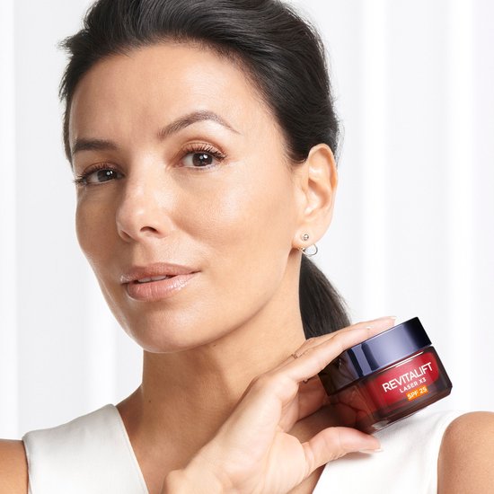 Een vrouw met bruin haar, Eva Longoria, houdt een L'Oréal Paris Revitalift Laser X3 dagcrème potje vast.