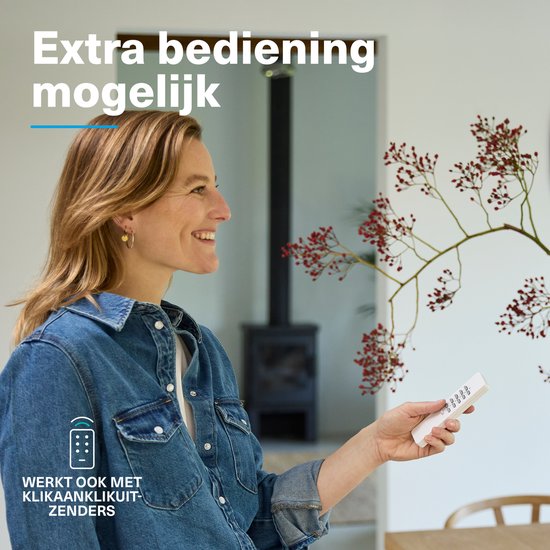 Vrouw met blonde haren, blauwe spijkerjas, houdt witte afstandsbediening vast. "Extra bediening mogelijk."
