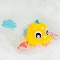 Gele badeend visje met rode vinnen en blauwe staart drijvend in bubbelend water.