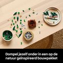 Table en bois avec des pièces LEGO de bambou détachées, des feuilles vertes et des pots.