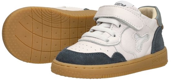 Twee witte leren sneakers met donkerblauwe suède details en bruine zolen.
