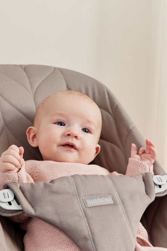 Close-up van baby in zandgrijs BabyBjörn wipstoeltje, met roze trui.