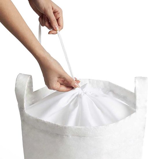 Hand sluit de trekkoordsluiting van een witte waszak met handvatten.
