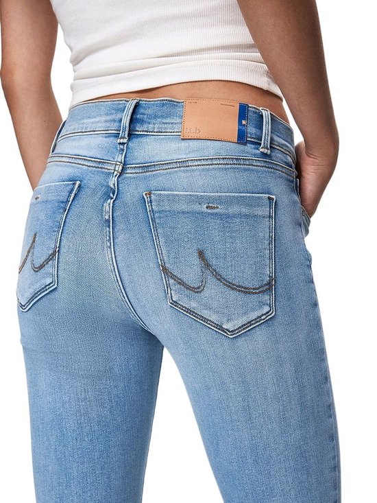 Detail van de achterkant van een lichtblauwe jeans met geborduurde zakken en een bruin label.
