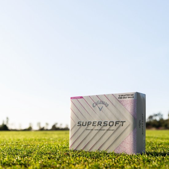 Doos Callaway SuperSoft golfballen met roze spetters op een grasveld met blauwe lucht.