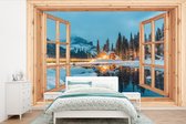 Behang - Fotobehang Winterlandschap - Natuur - Huis - Bergen - Doorkijk - Raam - Breedte 525 cm x hoogte 350 cm