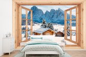 Behang - Fotobehang Doorkijk - Winterlandschap - Huisje - Bergen - Uitzicht - Breedte 525 cm x hoogte 350 cm