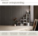 Rustige woonkamer met lamellenwand, witte open kast, plant en een schilderij.