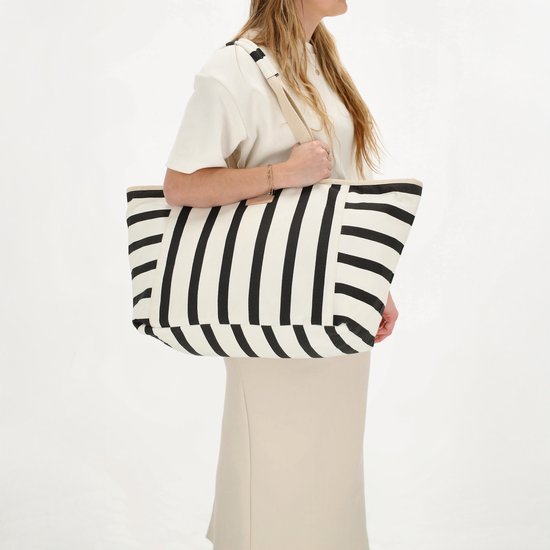 Vrouw met blonde haren met een gestreepte tas over haar schouder.