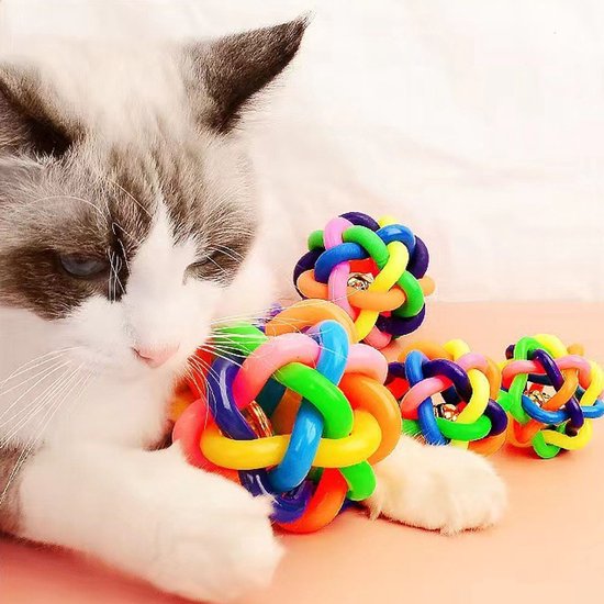 Een kat met een speelgoedbal van kleurrijke TPR-ringen, andere ballen liggen ernaast.