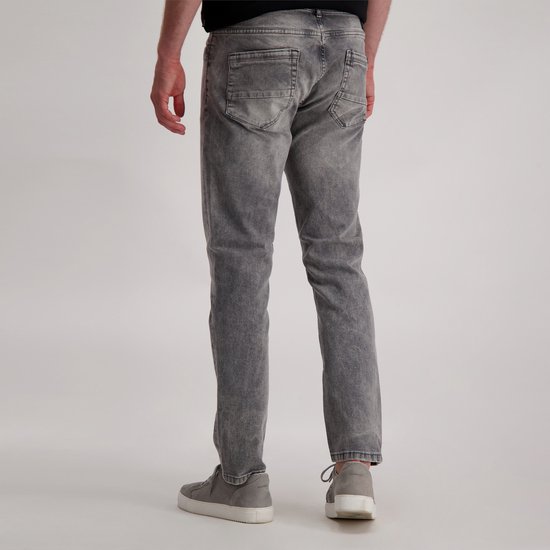 Model van achteren gezien in een grijze jeans met wassing en grijze sneakers.