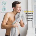 Man wrijft met een zachte, grijze handdoek over zijn gezicht. "De DoubleDry handdoeken zijn zeer aangenaam in gebruik."