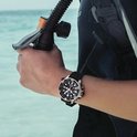 Man draagt een zwart Citizen Promaster duikhorloge om de pols, met duikapparatuur.