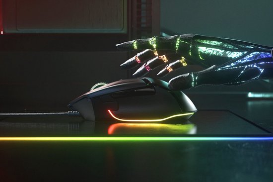 Een robotarm reikt naar de zwarte Razer Basilisk V3 gamingmuis met groene logo en RGB-accentverlichting.