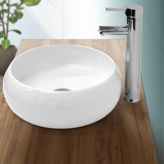 Lavabo blanc en céramique avec robinet chromé sur un meuble de salle de bain en bois.