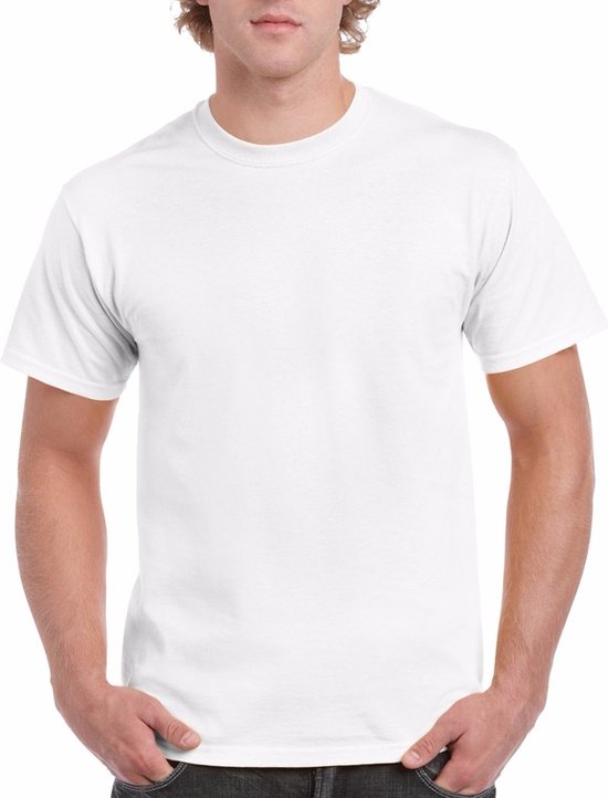 Un homme aux cheveux blonds bouclés porte un t-shirt blanc en coton Gildan. Les mains de l'homme sont dans ses poches.