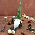 Un nain de Noël avec un bonnet pointu vert, une barbe blanche, des jambes rayées et des pieds beiges.