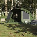 Olijfgroene tent in een bosrijke omgeving, met een stoel ernaast en opgestapelde boxen.