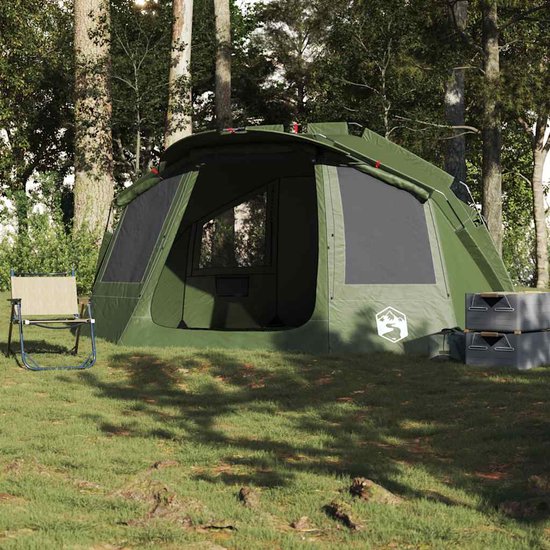 Olijfgroene tent in een bosrijke omgeving, met een stoel ernaast en opgestapelde boxen.