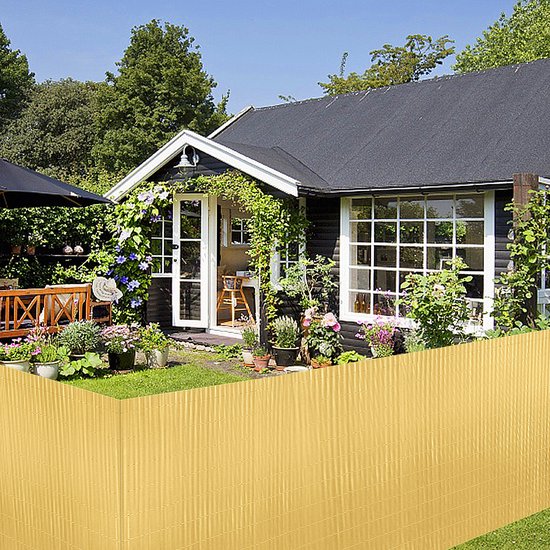 Gouden PVC zichtschermmat met verticale ribbels, geplaatst voor een schuur en tuin.