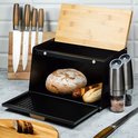 Boîte à pain noire Klausberg avec couvercle en bambou ouvert, avec du pain et des ustensiles de cuisine à côté.