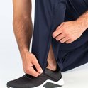 Donkerblauwe trainingsbroek met rits bij de enkel, gedragen door een man.