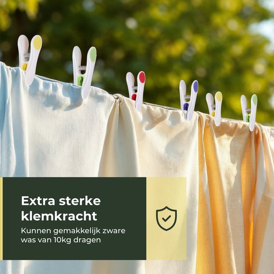 Witte wasknijpers met witte en groene accenten op een waslijn met kleding.