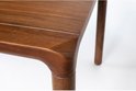 Close-up van de bruine walnoot eettafel met afgeronde hoeken en een subtiele naad in het midden.