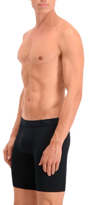 Man van de zijkant die zwarte Puma boxershorts met logo-elastische band draagt.