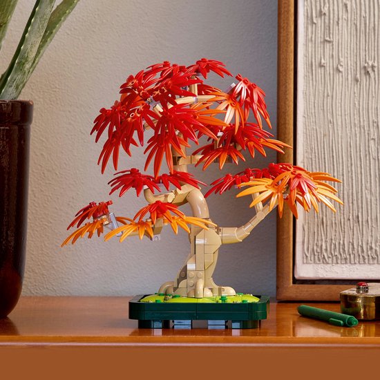 LEGO Japanse esdoorn boompje met rode en oranje bladeren op een dressoir.
