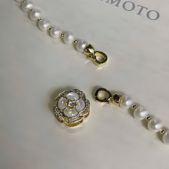 Gouden bloemvormige sluiting met zirkoon en parelmoer, met losse gouden karabijnhaken.