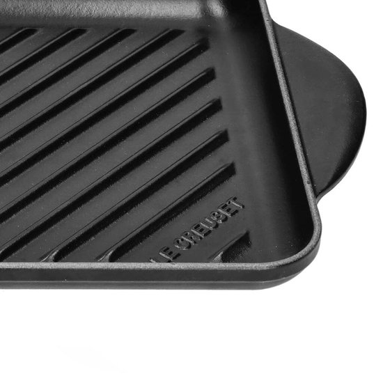 Zwart gietijzeren grillrooster met schuine ribbels en het Le Creuset logo.