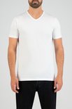 Man met baard draagt een wit V-hals T-shirt met korte mouwen en een spijkerbroek.