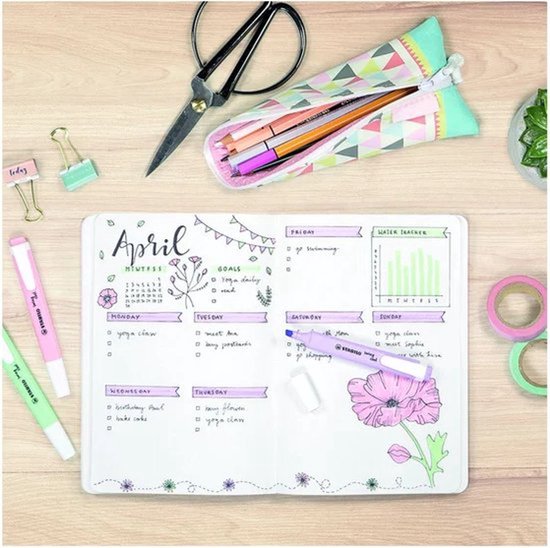 Bullet journal met kalender, doelen en water tracker, naast STABILO swing cool pastel markeerstiften en een etui.