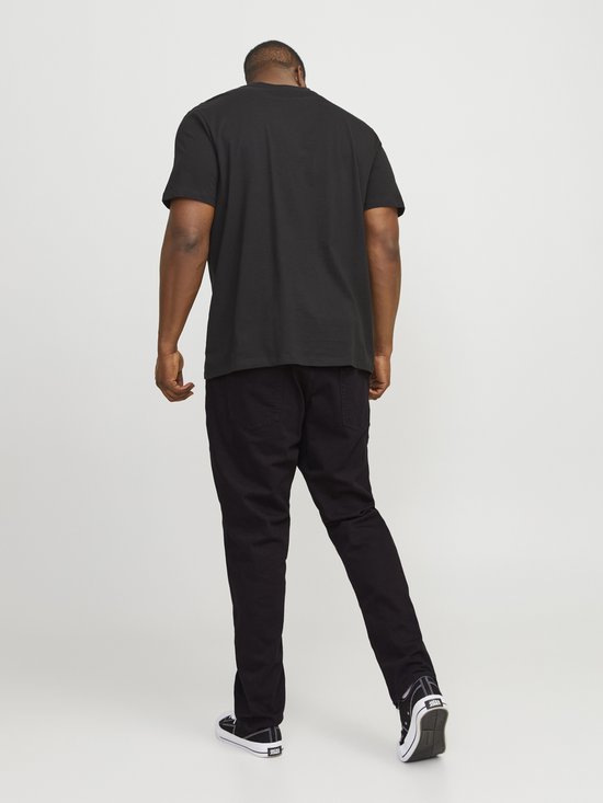 Man in een zwarte T-shirt, rug zichtbaar, en zwarte jeans met sneakers.