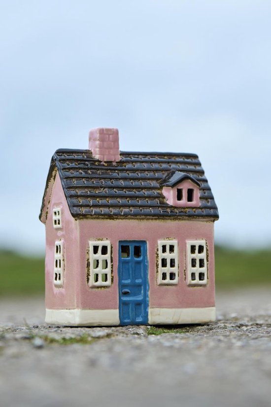 Roze keramieken huisje met blauwe deur, bruine dakpannen en een schoorsteen.