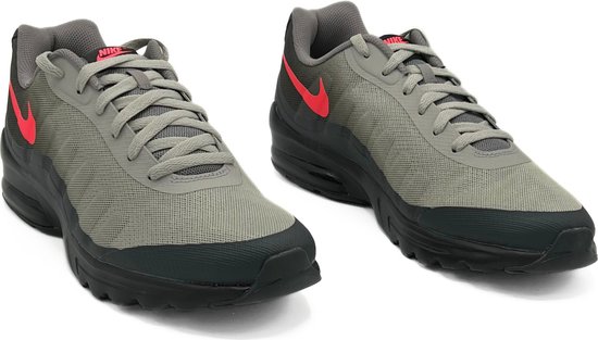 Paar grijze Nike Air Max Invigor sneakers met rode swoosh en zwarte zolen.