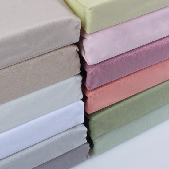 Pile de plusieurs draps-housse aux couleurs pastel comme le rose, le vert et le jaune.