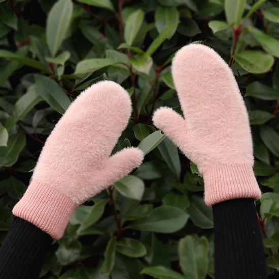Een paar zachte, roze, pluizige dameswanten met gebreide roze boorden, gedragen aan handen met zwarte mouwen.
