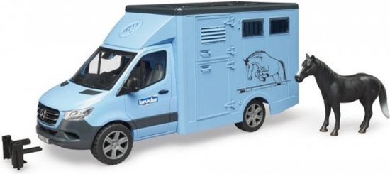 Lichtblauwe Bruder paardenwagen met een paard ernaast en een trekhaakje. Dewagen heeft een afbeelding van een springend paard.