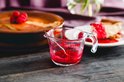 Glazen Pyrex maatbeker met rode bessensaus, naast een taart en taartpunt.