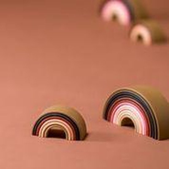 Twee Dëna regenboog stapelsets in huidtinten op een bruine ondergrond.