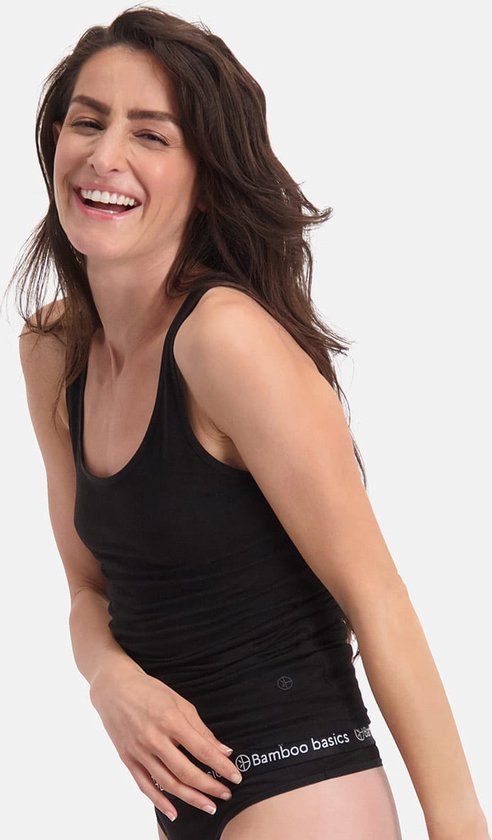 Lachende vrouw met donker haar, draagt een zwarte singlet en ondergoed.