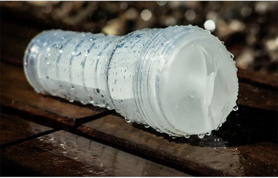 Duidelijke Fleshlight Ice Crystal, bedekt met waterdruppels, op een houten ondergrond.