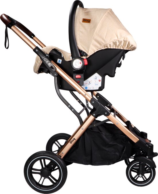 Beige kinderwagen met goudkleurig frame, bruine handgrepen, met een zwart autostoeltje erop.