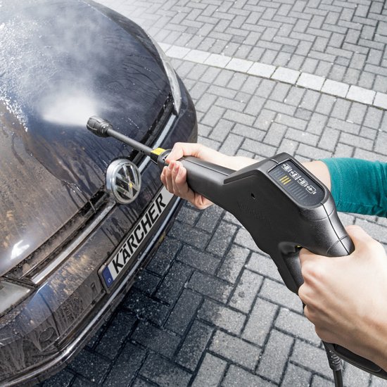 Hand met hogedrukreiniger spuitend op de motorkap van een auto.